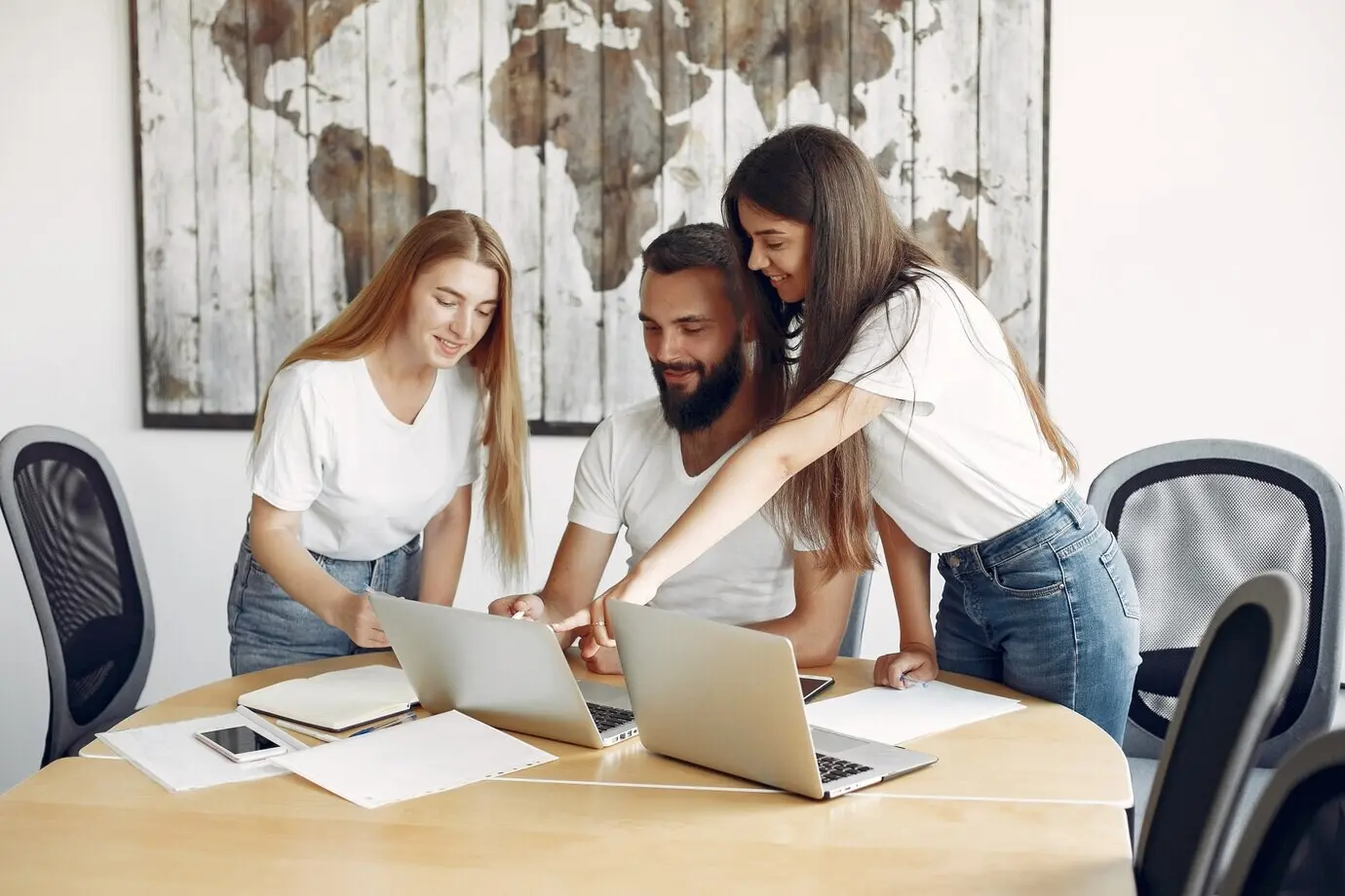 Молодая команда работает сообща, используя ноутбук.